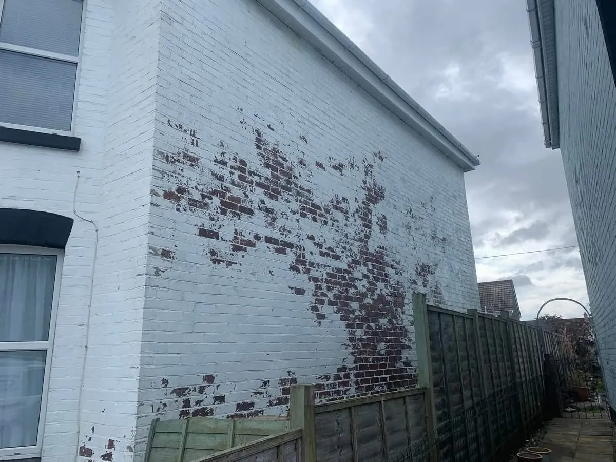 Peeling paint on a brick wall before redecoration in Crediton
